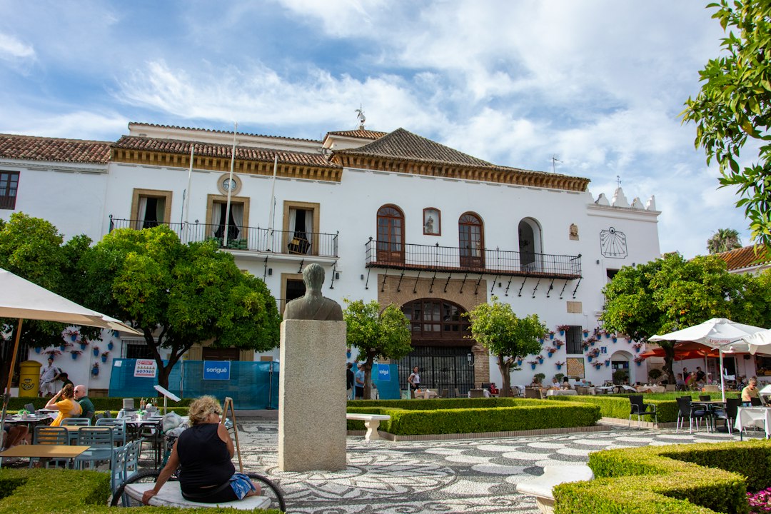 White buildings and a statue in a sunny plaza in Marbella, Andalusia